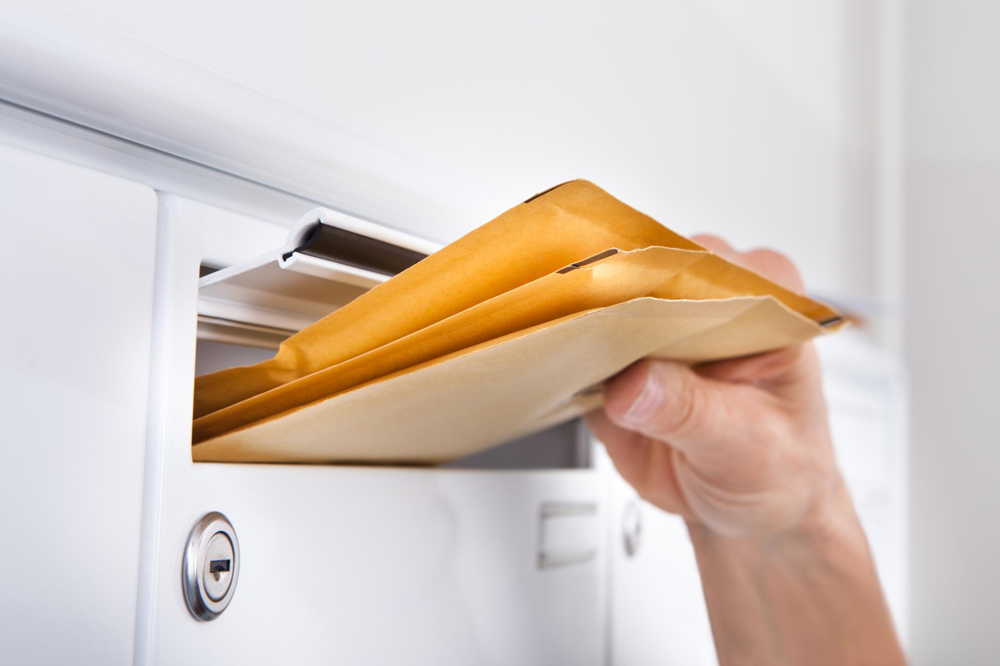 Yellow envelopes being slipped into a rental mailbox
